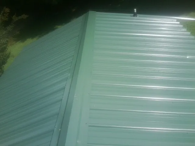 New green metal panels meeting at the ridge of a roof — Flat Roof Repair work by our crew in Cottonport