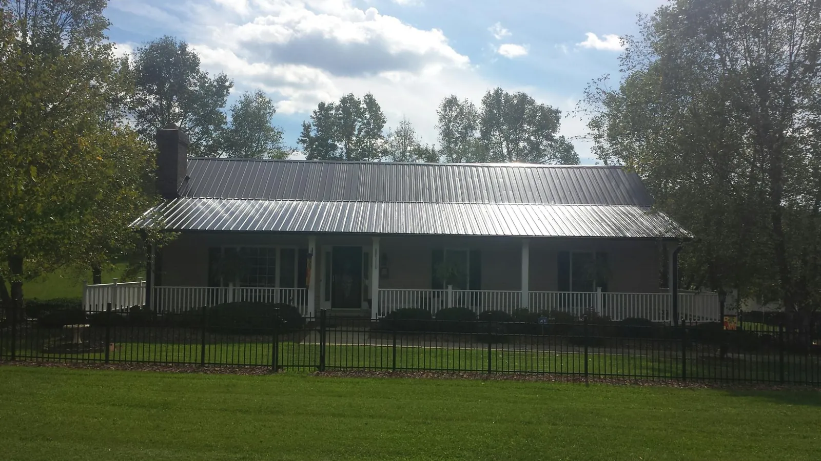 Gray metal roof on a brick ranch with a full width front porch — Gutter Guard Installation work by our crew in Cottonport