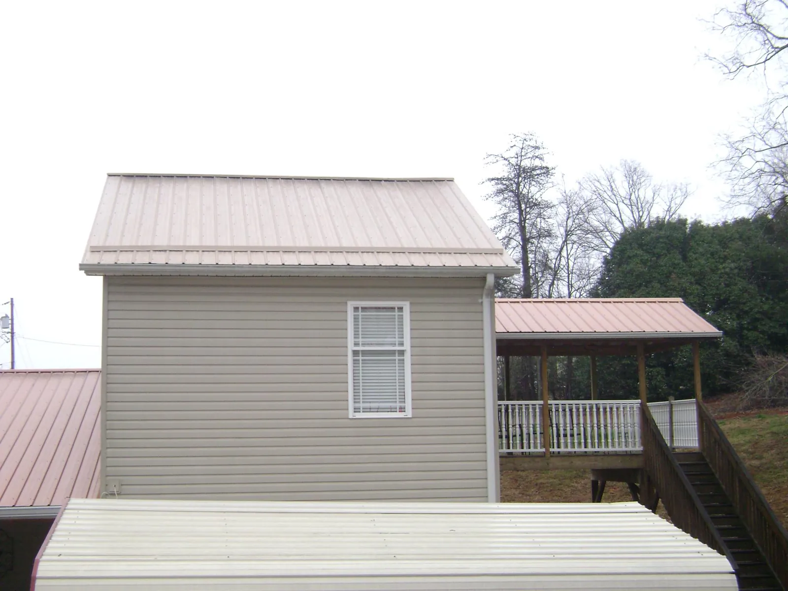 Tan metal roofs on a two story addition and attached porch, from a Roof Replacement job in Cottonport