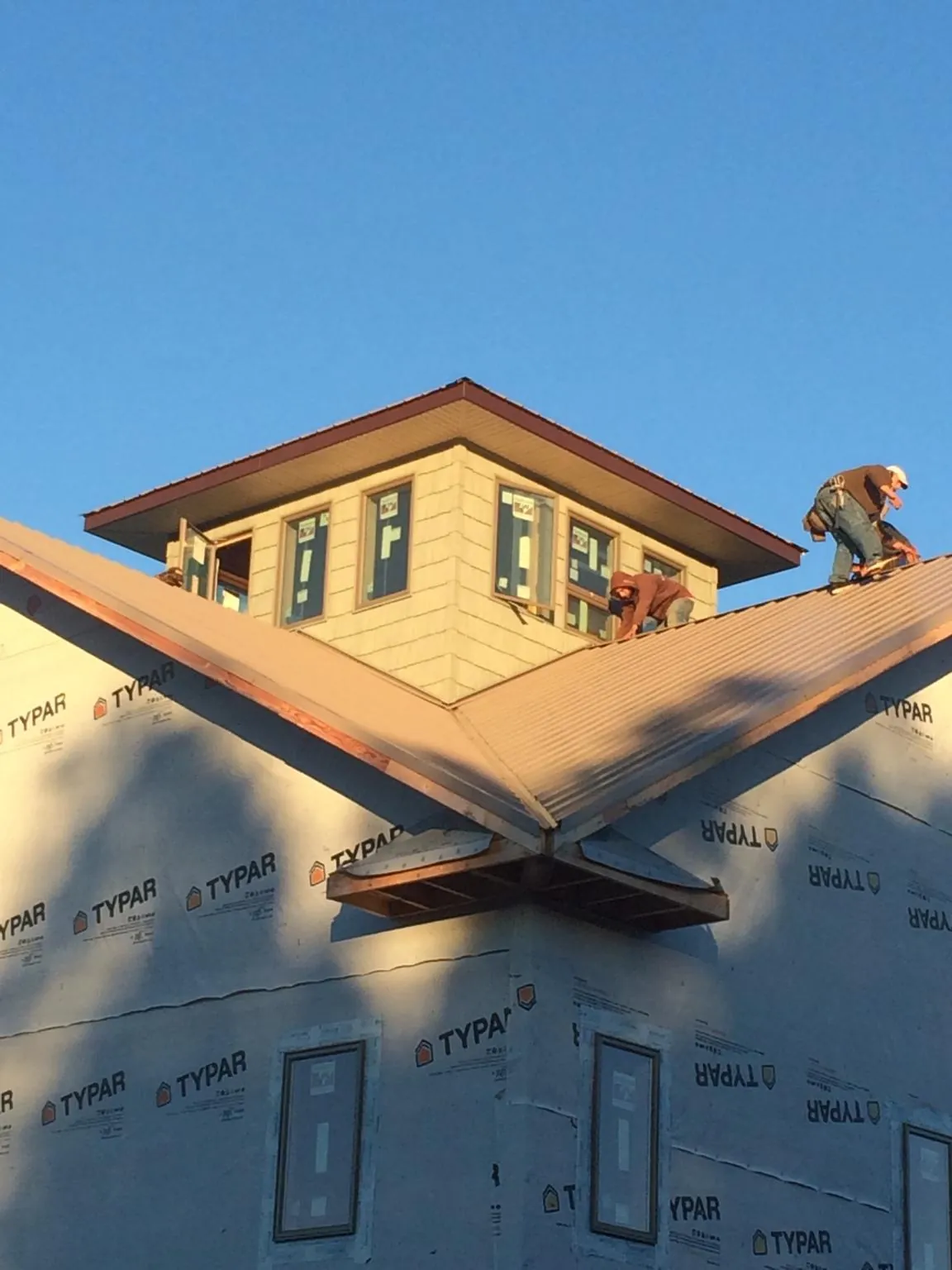 Roofers working around a rooftop cupola on a new metal roof at sunset — Roof Waterproofing in Cottonport by Roofing Brothers